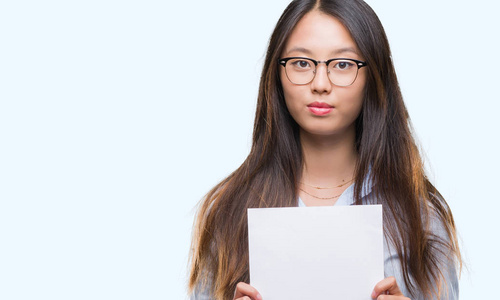 年轻的亚洲女人,在孤立的背景上拿着白纸,聪明的脸上有自信的表情