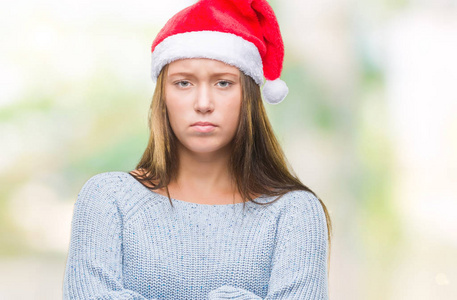 年轻美丽的高加索女人戴着圣诞帽，在孤立的背景怀疑和紧张的不赞成的表情上，交叉的手臂。 消极的人。