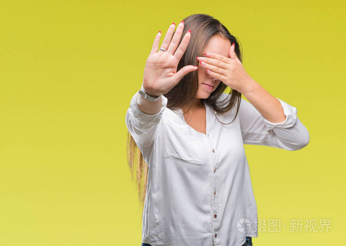 年轻的高加索美女戴着眼镜在孤立的背景上用手遮住眼睛用悲伤和恐惧的