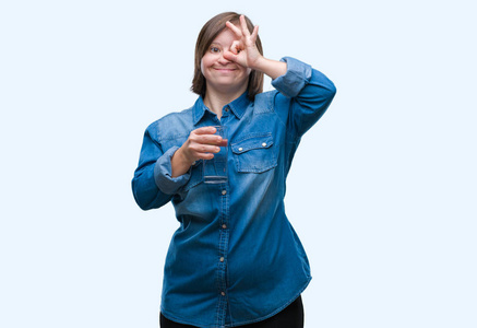 年轻的成年女性，患有唐氏综合症，在孤立的背景下喝水，快乐的脸，微笑，做OK标志，用手盯着手指