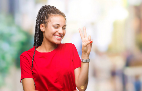 年轻的辫子非裔美国女孩在孤立的背景上微笑，快乐的脸对镜头眨眼，做胜利标志。 二号。
