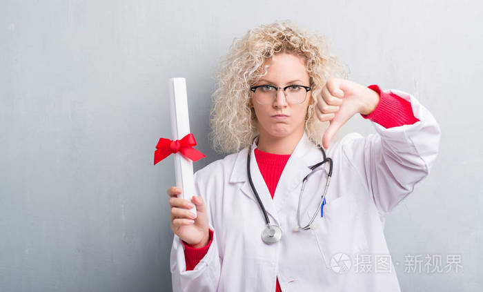 女医生在灰色的墙上抱着愤怒的脸消极的迹象显示不喜欢拇指拒绝的概念