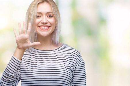 年轻的金发女子在孤立的背景显示和指着第五个手指，同时微笑自信和快乐。