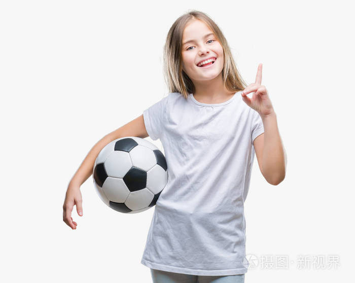 年轻漂亮的女孩抱着足球球在孤立的背景下惊讶的想法或问题手指和快乐