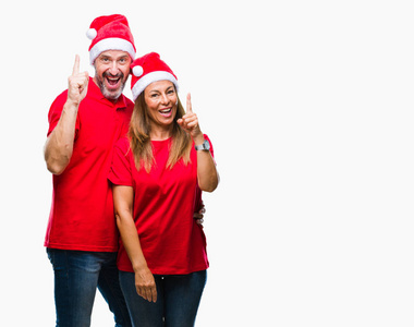 中年西班牙裔夫妇戴着圣诞帽，在孤立的背景上指着成功的想法。 退出并快乐。 一号。