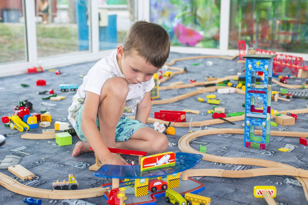 小孩子在地板上玩木铁路。 小男孩在玩木火车
