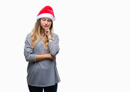 年轻漂亮的金发女人戴着圣诞帽，在孤立的背景下思考，看起来疲惫，厌倦了交叉双臂的抑郁问题。