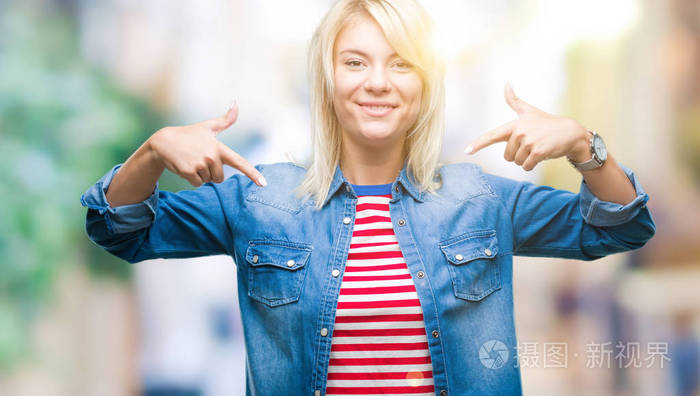 年轻漂亮的金发女人穿着牛仔夹克在孤立的背景上自信地微笑着用手指