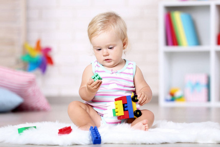 小女孩坐在白色地毯上玩玩具图片