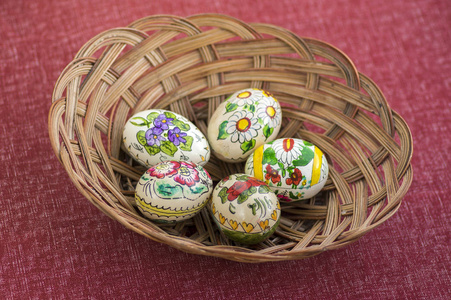 红橙色的复活节彩蛋在棕色柳条篮子里，传统的复活节静物彩花五个鸡蛋