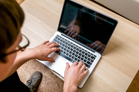 集中的年轻人带着眼镜在家里的办公室里用笔记本电脑工作.