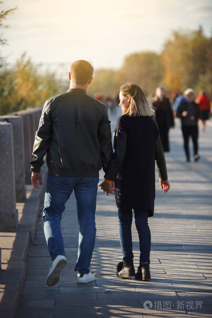 年轻夫妇男孩和女孩在秋天公园散步堕落外面的年轻人和女人幸福的家庭