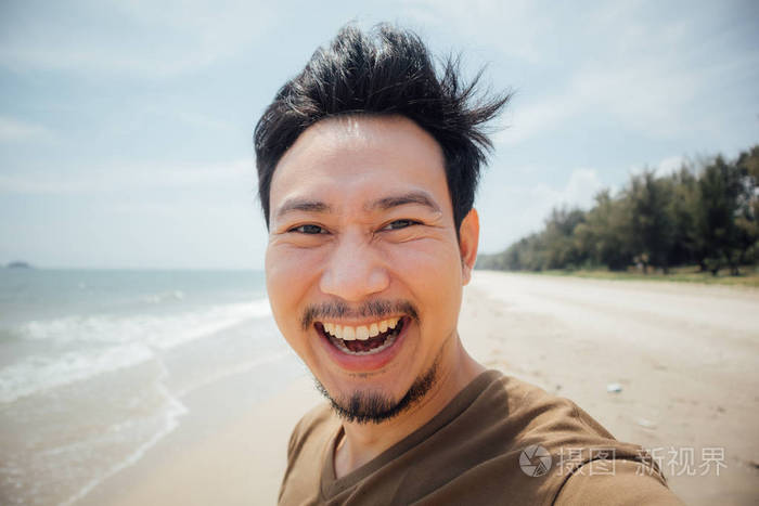 亚洲男人欢快快乐的脸在海滩上自拍