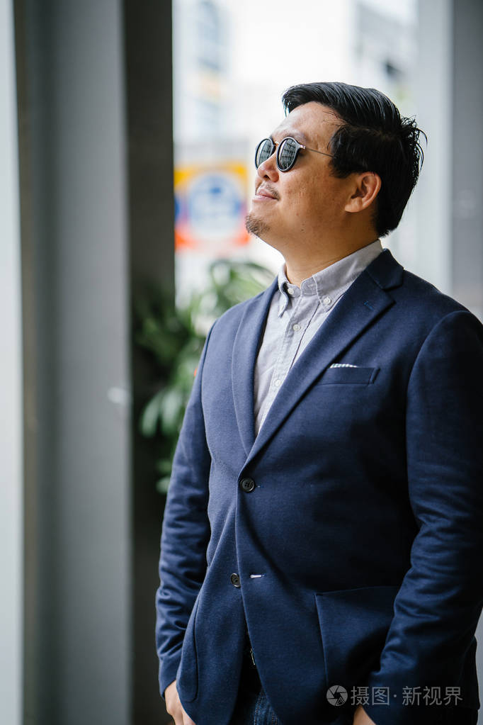 一位中年中国亚裔男子(新加坡人)的肖像,穿着智能休闲,站在城市里.