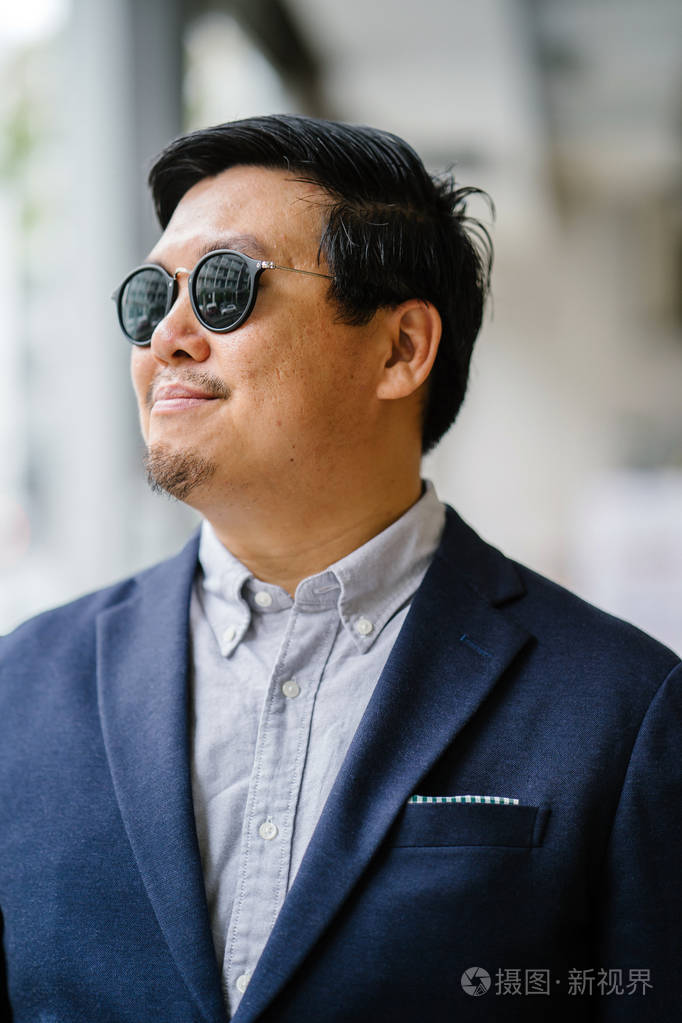 照片 一位中年中国亚裔男子(新加坡人)的肖像,穿着智能休闲,站在城市