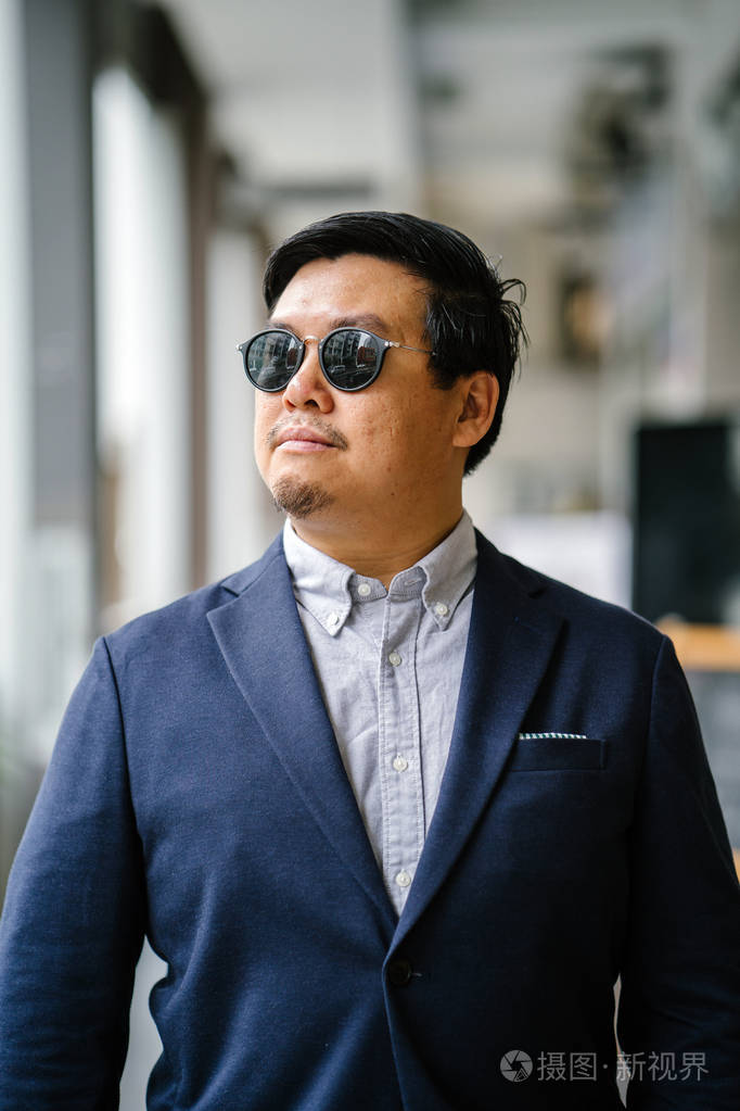 一位中年中国亚裔男子新加坡人的肖像穿着智能休闲站在城市里他穿着