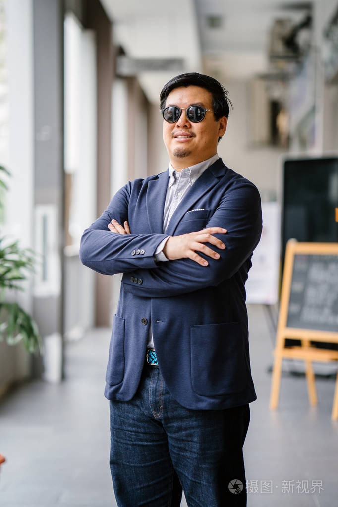 一位中年中国亚裔男子新加坡人的肖像穿着智能休闲站在城市里他穿着