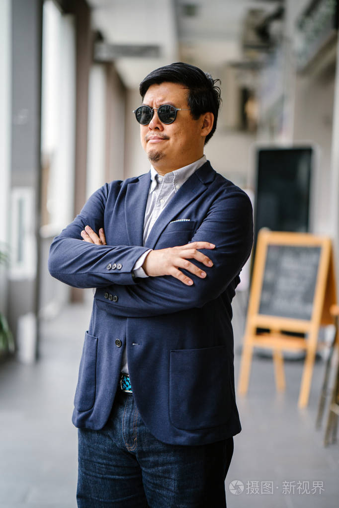 一位中年中国亚裔男子新加坡人的肖像穿着智能休闲站在城市里他穿着