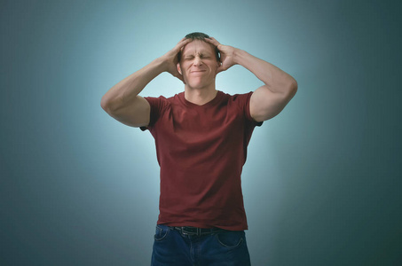 despong绝望的人在压力下用双手抱着他的头,孤立在蓝色的背景上.照片