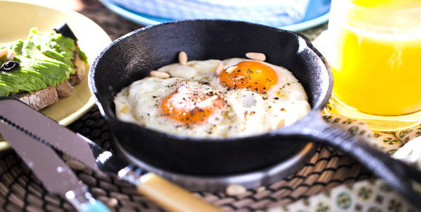 煎蛋。 在煎锅上关闭煎蛋的视图。 在铸铁锅和黑色背景上用欧芹腌制和五香煎蛋。