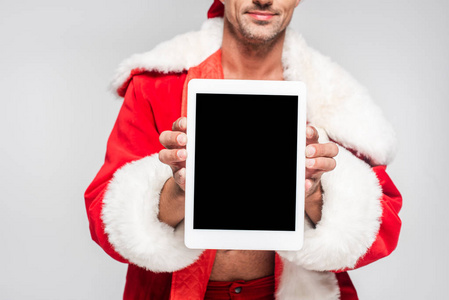 身着圣诞老人服装，手持数码平板电脑，屏幕空白，灰色隔离