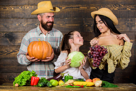 家庭乡村风格的农民市场与秋季丰收。父母和女儿庆祝收获节日南瓜蔬菜水果。收获节的概念。家庭农民与收获木背景