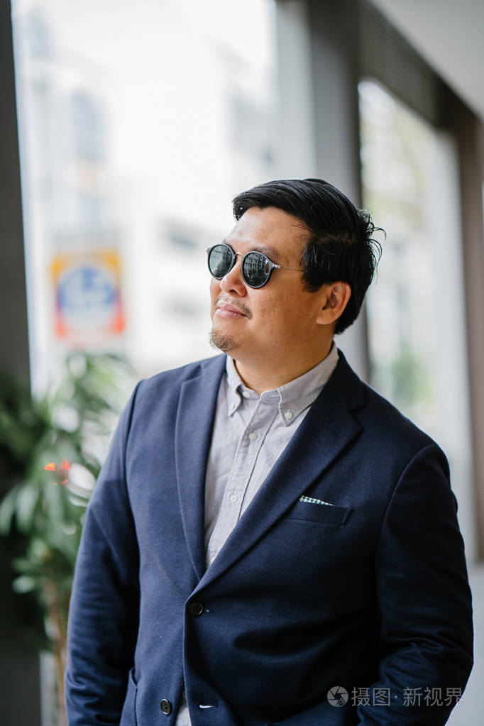 一位中年中国亚裔男子(新加坡人)的肖像,穿着智能休闲,站在城市里.