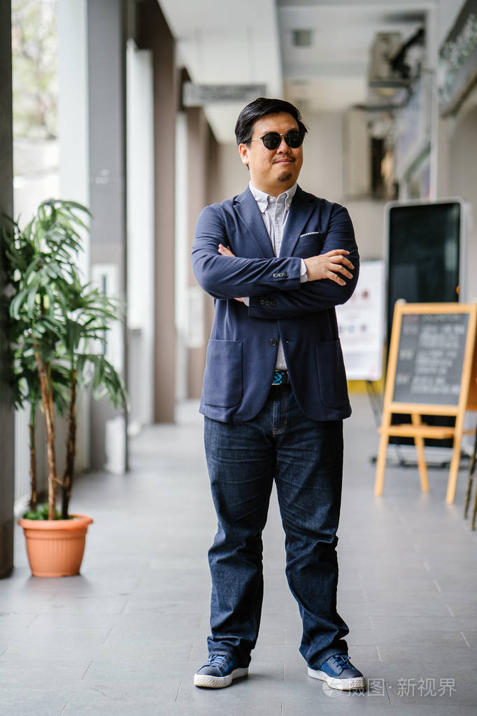 一位中年中国亚裔男子(新加坡人)的肖像,穿着智能休闲,站在城市里.