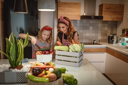 快乐的母亲和她的女儿喜欢在家里的厨房一起做和吃健康的饭菜。