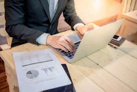 商人穿西装打领带,用笔记本电脑看文书工作.