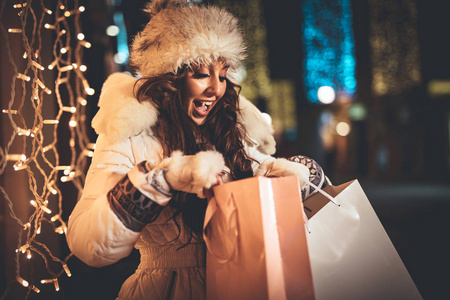 在圣诞节的时候，带着礼物在城市街道上玩得很开心的年轻女人。
