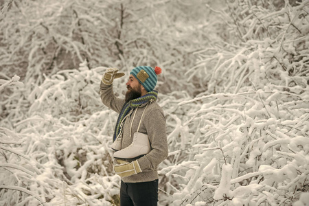 长胡子的人在雪地森林里带着冰鞋。冬天的护肤和胡须护理。温度，冰冻，寒流，降雪。冬季运动和休息，圣诞节。穿热夹克的人，冬天胡须暖和