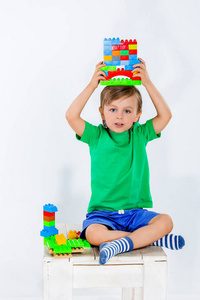 小男孩在室内玩很多五颜六色的塑料积木。