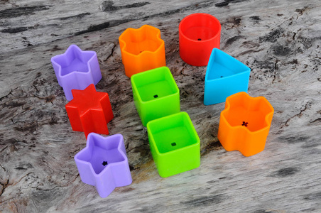 s toy blocks in various shapes made of plastic on wood grain bac