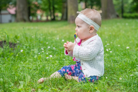 小女孩坐在草地上吮吮奶嘴。