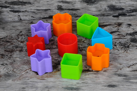 s toy blocks in various shapes made of plastic on wood grain bac