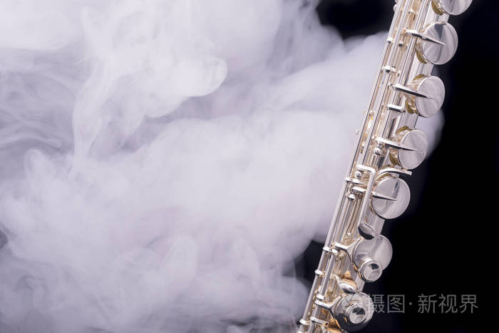 一种镀银的阿尔托长笛在黑色的背景上冒烟