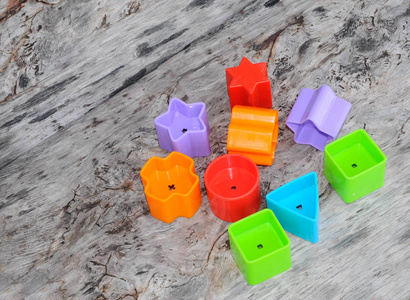 s toy blocks in various shapes made of plastic on wood grain bac