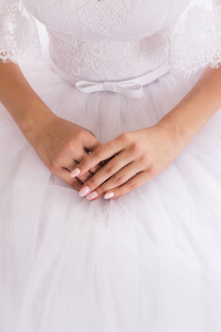 新娘精心修剪的手上有漂亮的指甲，穿着白色的婚纱