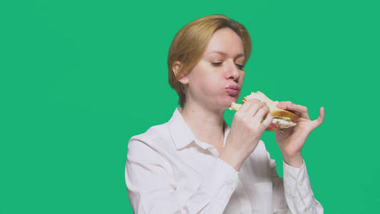 女商人在绿色背景下吃三明治。快速午餐概念