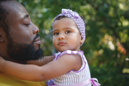 非裔美国父亲抱着一个可爱的小穆拉托女儿。