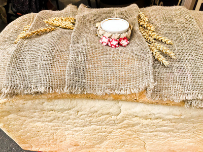 一个大的, 巨大的长方形的白色自制小麦面包, 壳和盐。俄罗斯传统, 以满足客人。女性手做的面包