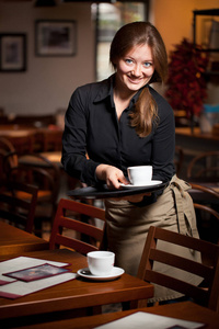 女服务员拿着咖啡杯托盘在咖啡馆的肖像