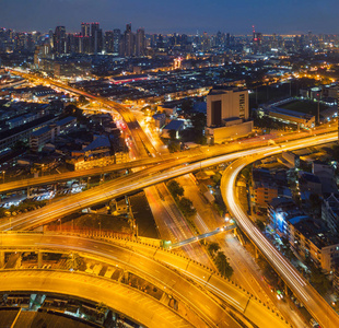 汽车在桥路上行驶，形成曲线公路与摩天大楼建筑。 泰国夜间曼谷城市概念城市建筑结构中快速路的鸟瞰图。