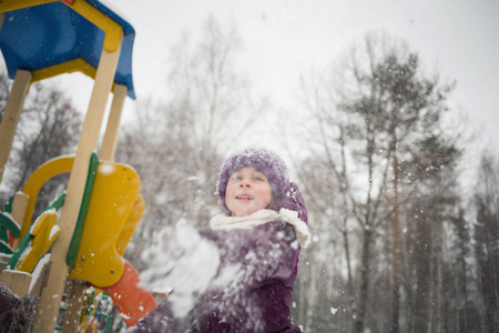小女孩在冬季公园玩雪球。 户外娱乐