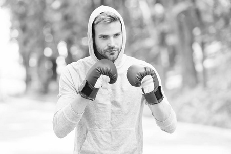 大日子的训练。男子运动员集中面部与运动手套练习拳击拳, 自然背景。拳击帽头练习打拳拳。运动员拳击手训练与拳击手套