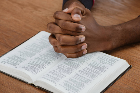 美国黑人男子在木桌上用圣经祈祷