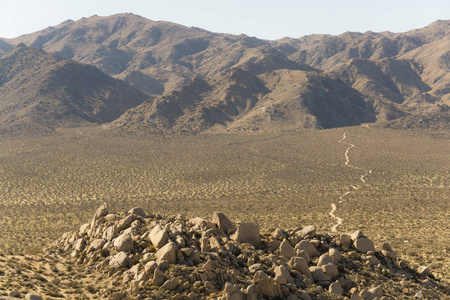 一条安静的尘土飞扬的道路蜿蜒穿过加州南部的岩石沙漠地板