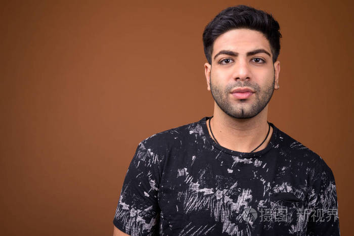 年轻英俊的印度人反对棕色背景