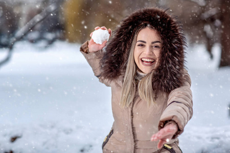 快乐的年轻女人在雪天打雪仗。 冬季概念